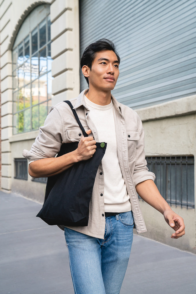 Person holds a black tote bag outside