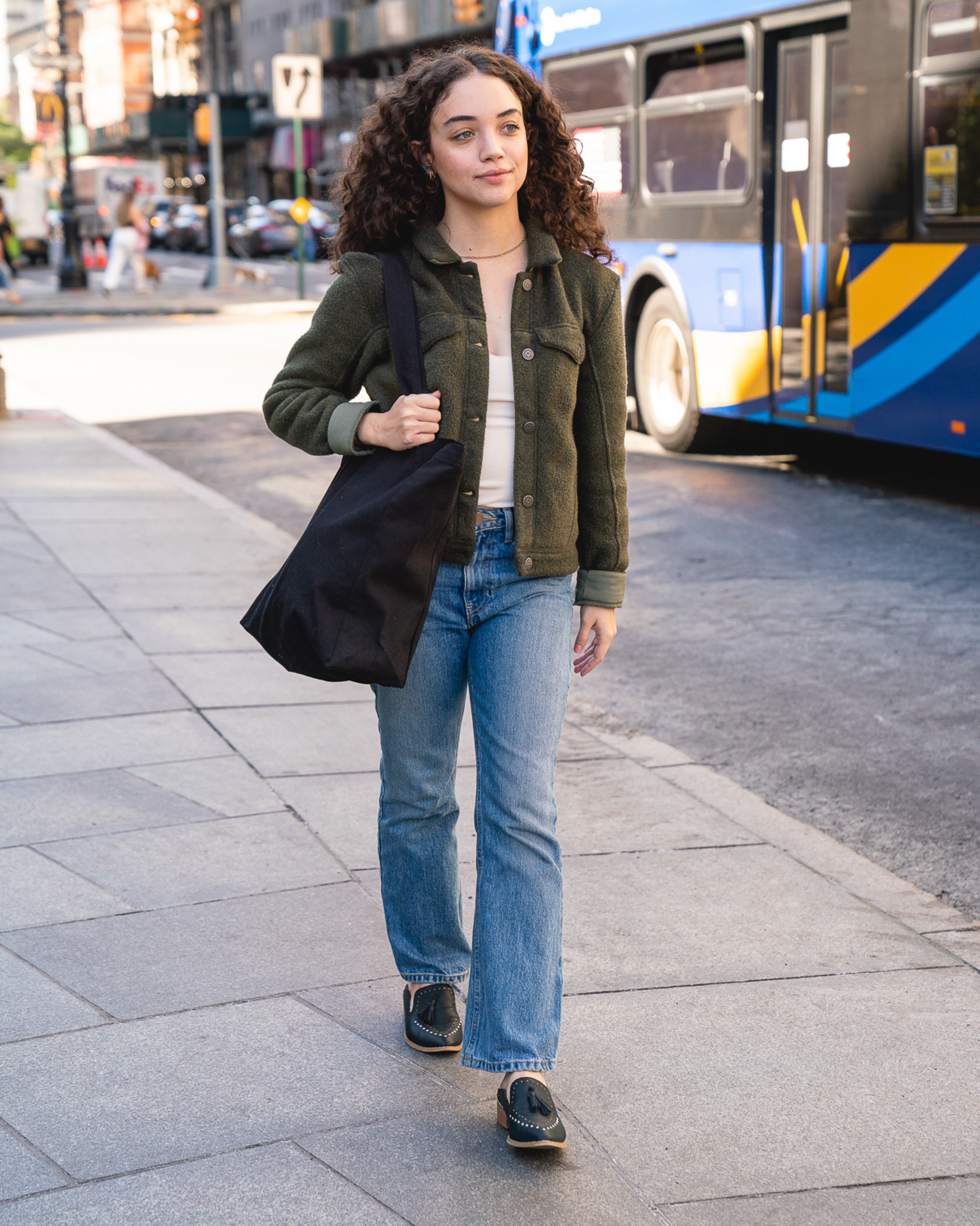 Woman walking on a city street holding a black bag